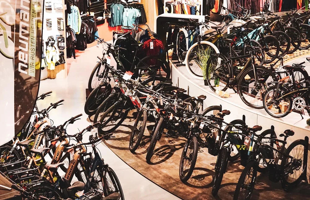 Fahrradgeschäft mit mehreren Mountainbikes, E-Bikes und Zubehör. Marke Neumann sichtbar, geeignet für Sport und Freizeit.