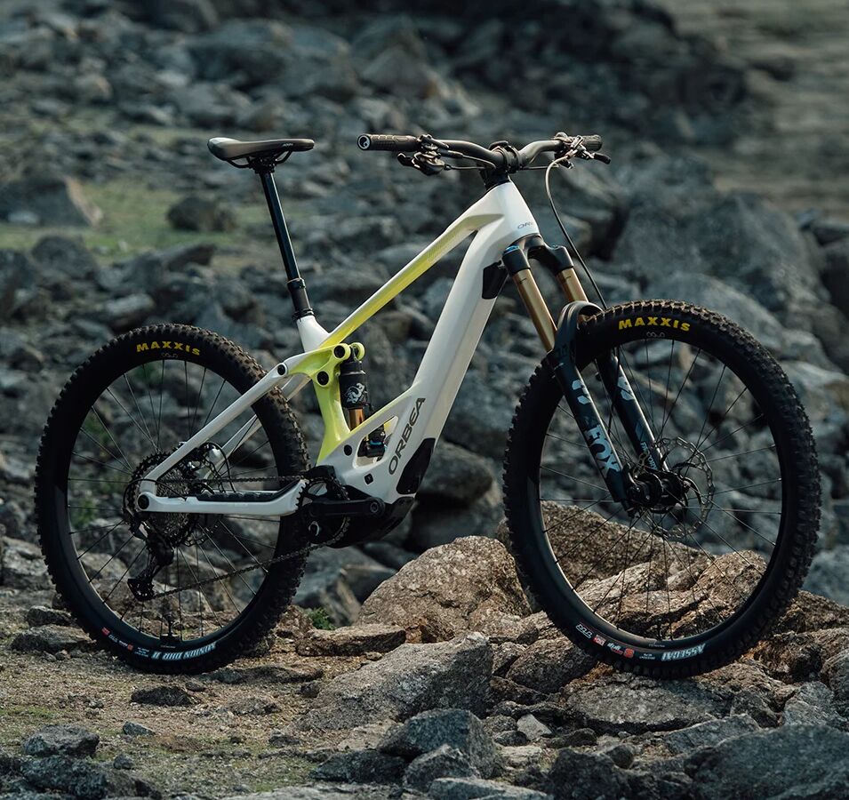 Orbea Wild E-Mountainbike auf felsigem Gelände, mit robusten Maxxis-Reifen und auffälligem gelben Detail am Rahmen.