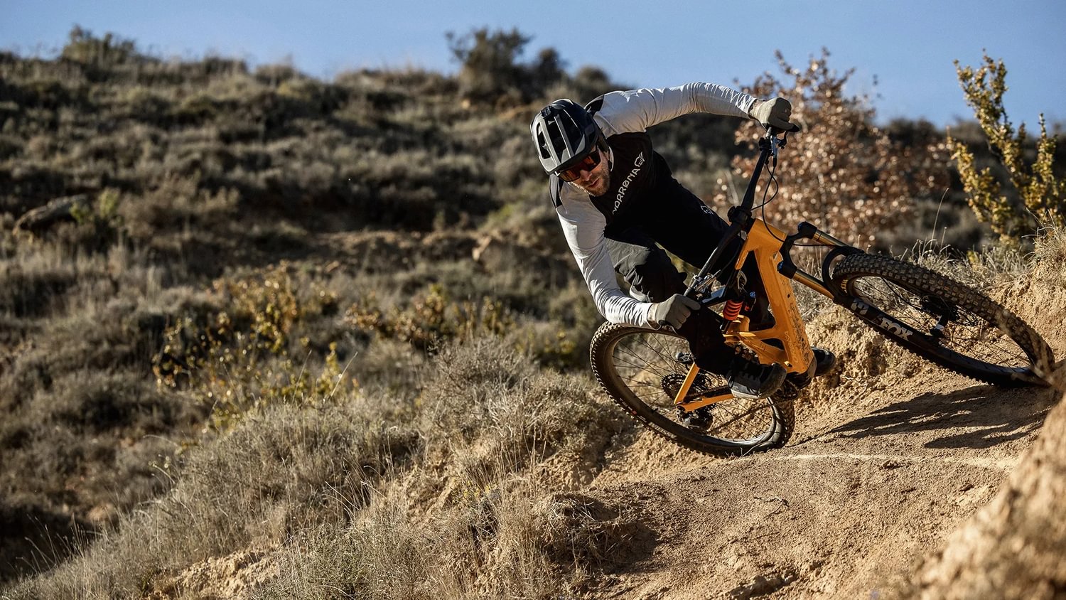 Mountainbiker auf dem Orbea Rise E-Mountainbike fährt schnell einen sonnigen, staubigen Hang hinab.