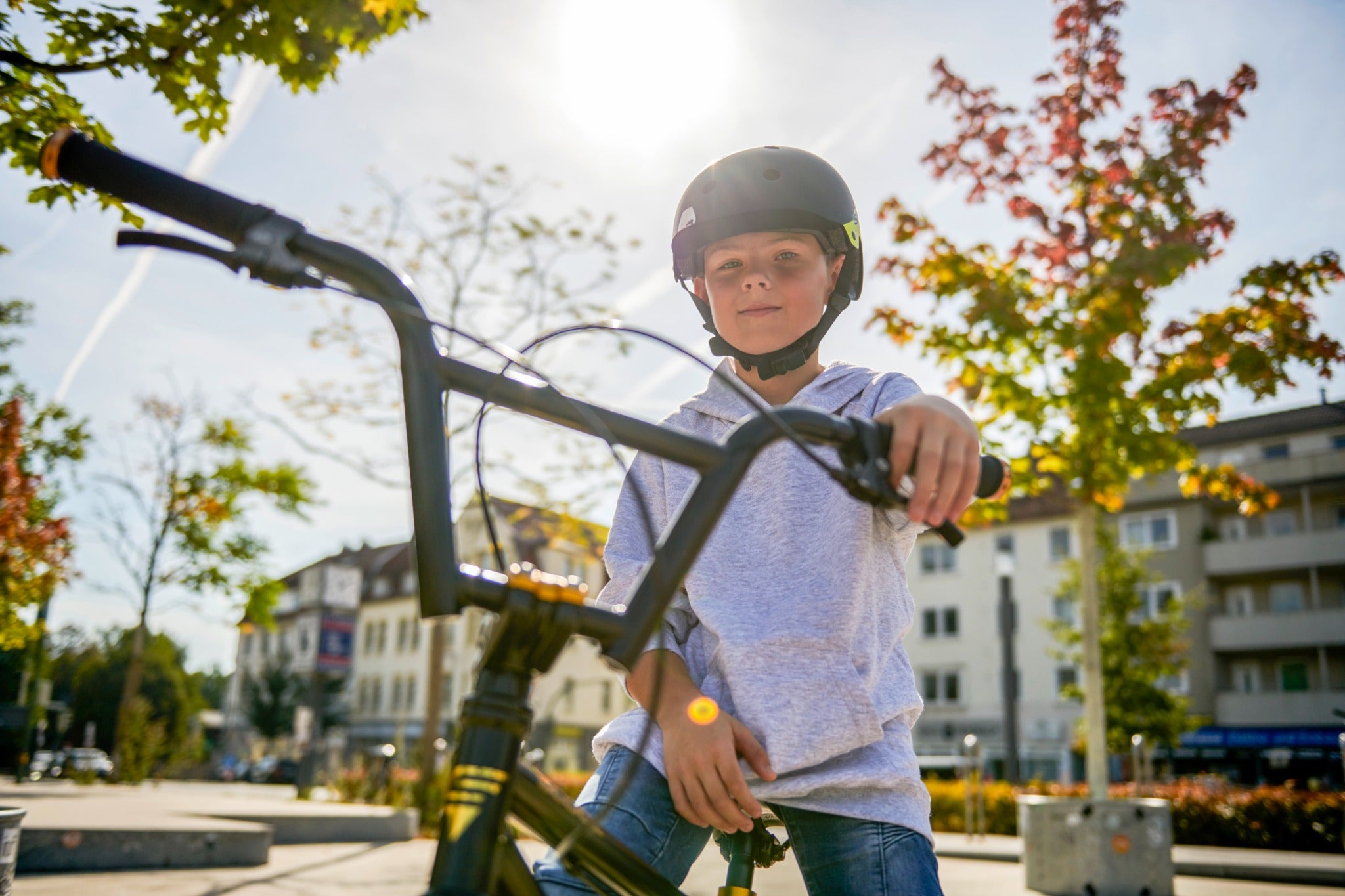 Junge mit Fahrrad und Helm in einem sonnigen Park. Ideal für aktive Kinder im Freien.