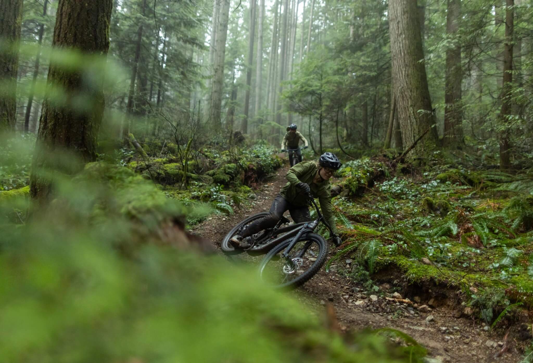 Mountainbiker auf Trek E-MTBs im dichten, grünen Wald auf einem schmalen Pfad. Ideal für Abenteurer im Gelände.