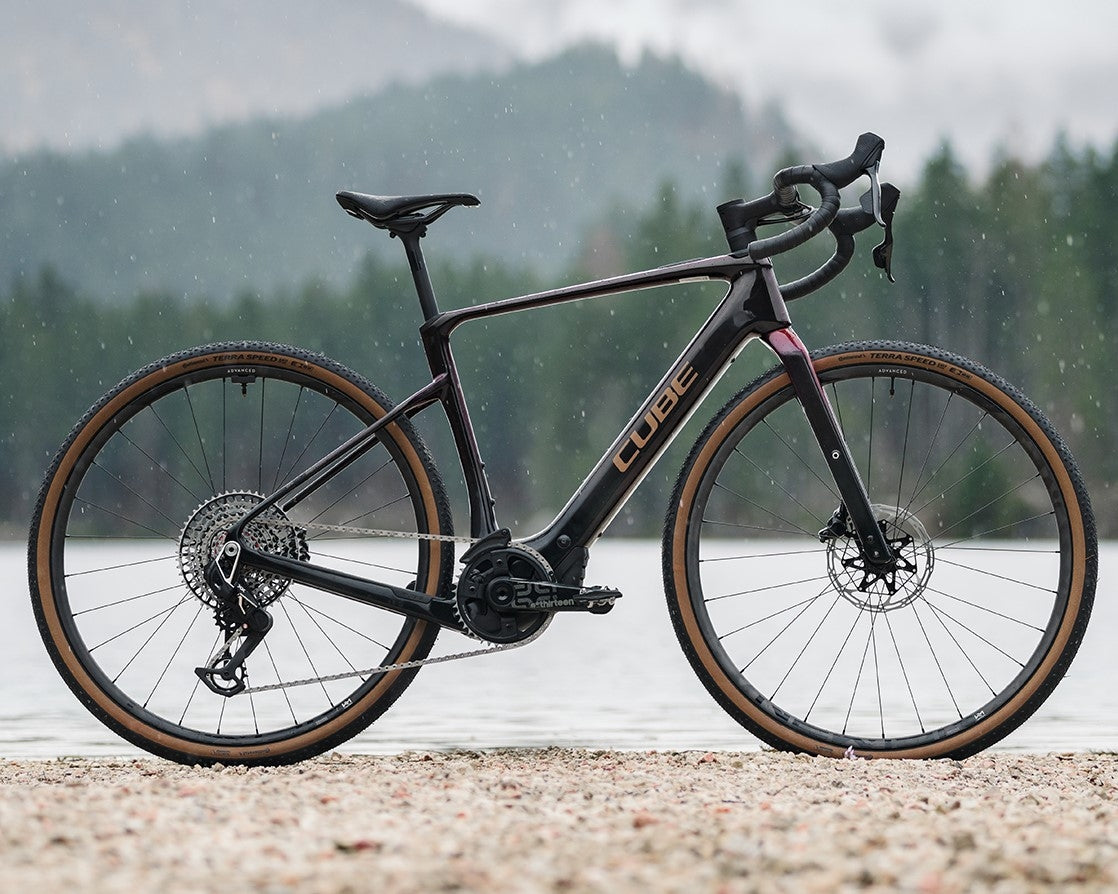 Cube Nuroad Hybrid E-Bike vor Seehintergrund, geeignet für Gravel und All-Terrain Touren bei verschiedenen Wetterbedingungen.