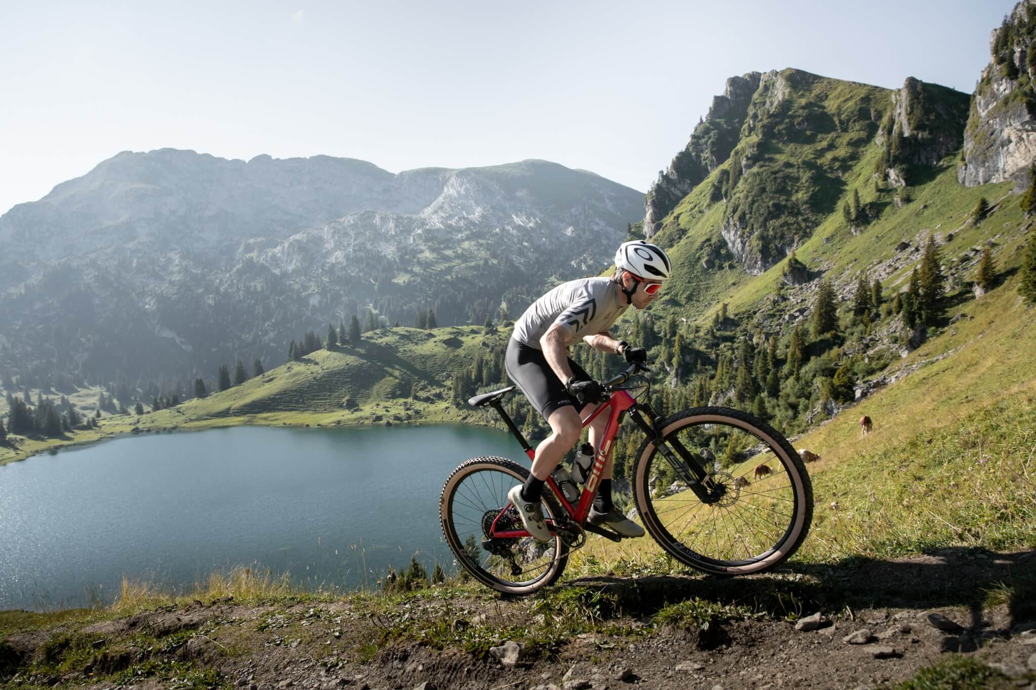 Mensch fährt BMC Mountainbike an einem See in bergiger Natur, ideal für sportliche Outdoor-Aktivitäten.