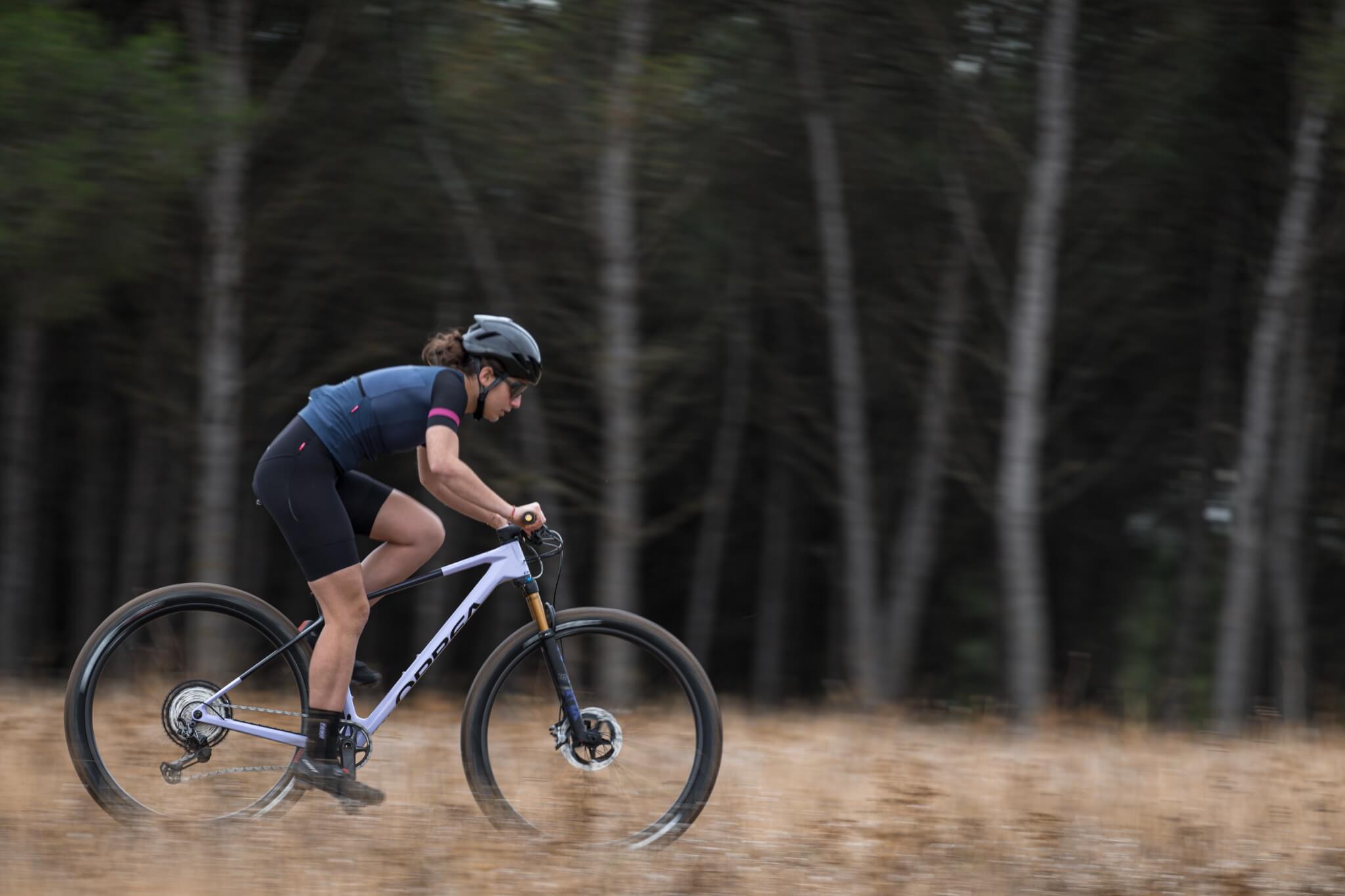 Radfahrerin auf Orbea Hardtail-Mountainbike im Wald; geeignet für Offroad-Enthusiasten.