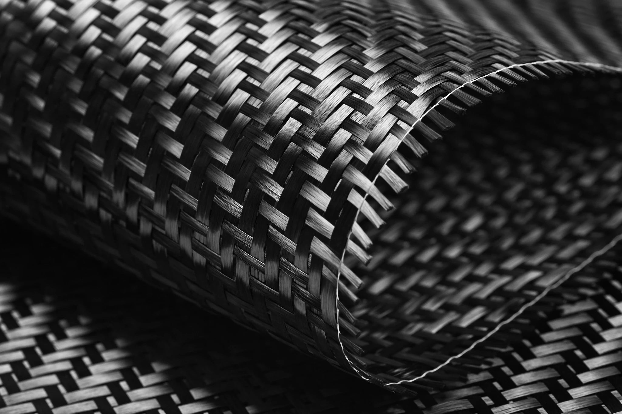 Geflochtene schwarze Kohlefaserstruktur, vielseitig einsetzbar für industrielle Anwendungen und Designprojekte.