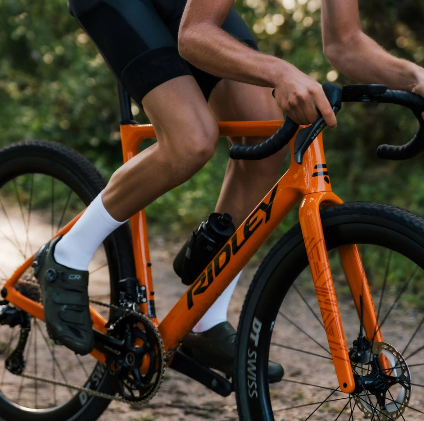 Oranges Ridley Gravel Bike, im Einsatz auf Waldweg; geeignet für Outdoor-Radsportler.