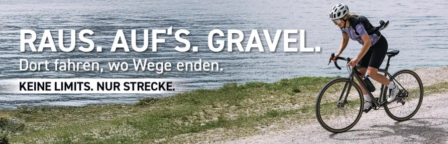 Frau fährt Gravelbike am Seeufer entlang, trägt Helm und sportliche Kleidung, Text im Bild: "Raus. Auf's. Gravel."