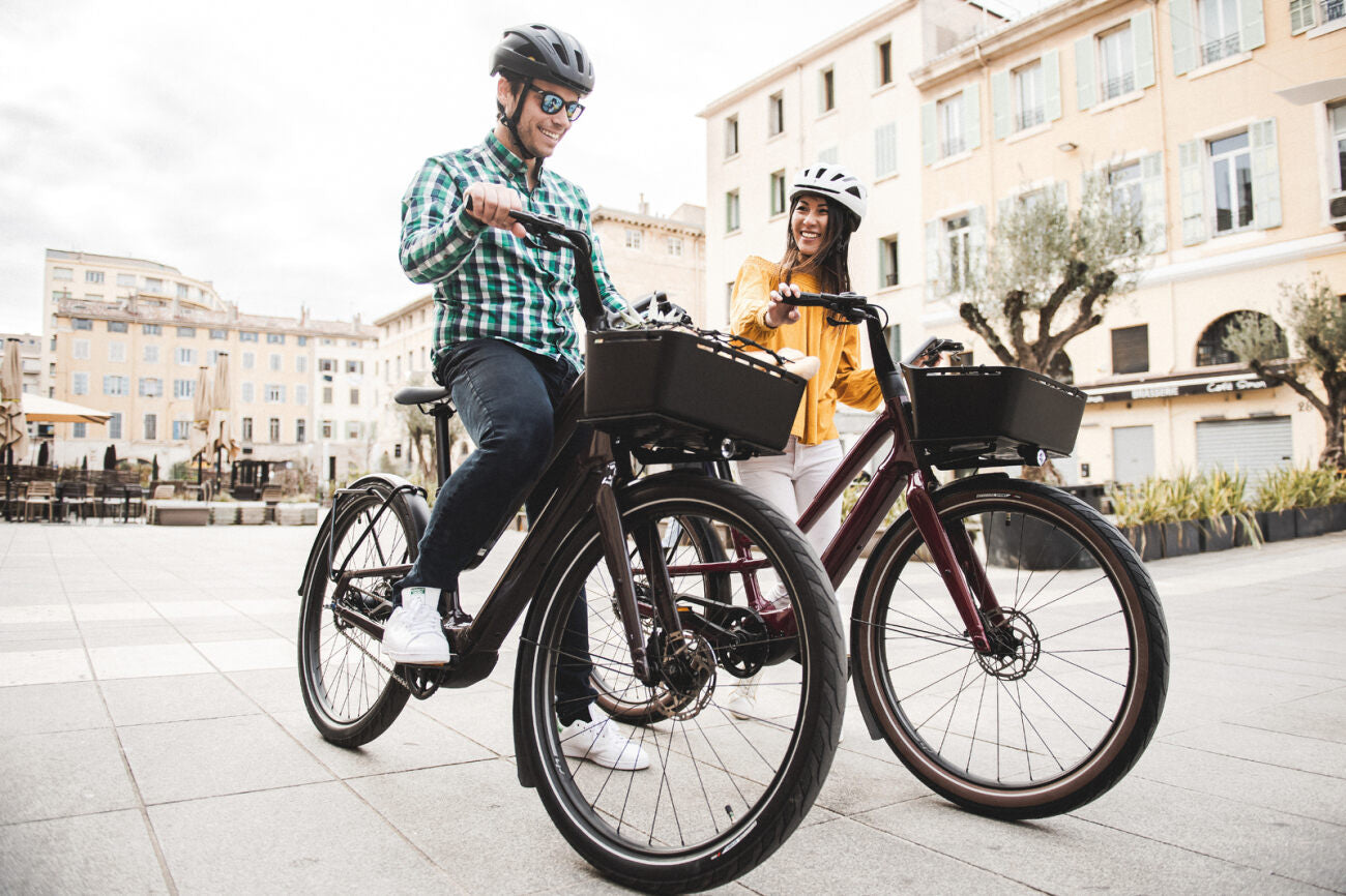 Zwei Personen fahren Specialized E-Bikes in einer Stadtumgebung, beide tragen Helme.