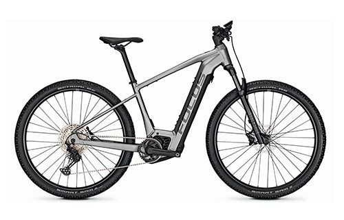 Silbernes Focus E-Hardtail-Mountainbike, geeignet für Geländefahrten, mit robustem Rahmen und breiten Reifen.