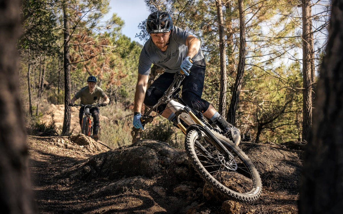 Zwei Mountainbiker fahren durch einen bewaldeten Trail. Der vordere Fahrer nutzt ein Focus E-Mountainbike.