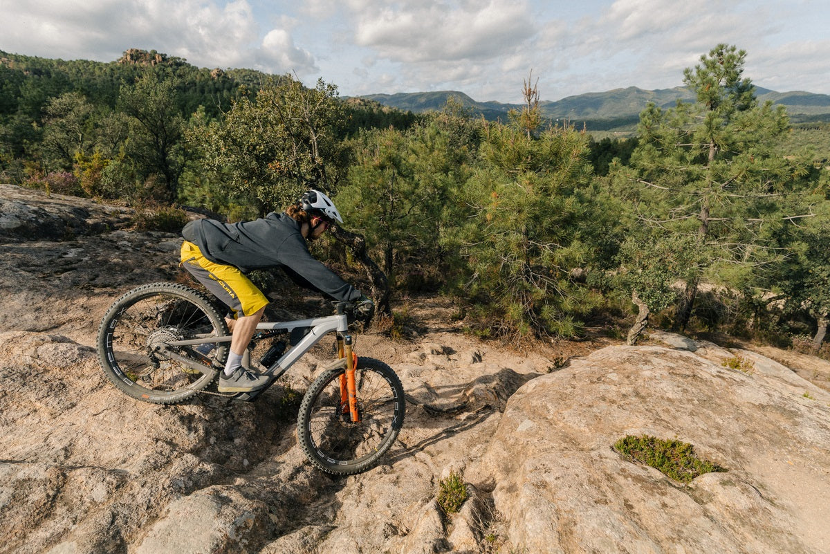 Mountainbiker auf einem Focus E-MTB fährt steinigen Trail im Wald bergab; ideal für Offroad-Enthusiasten.