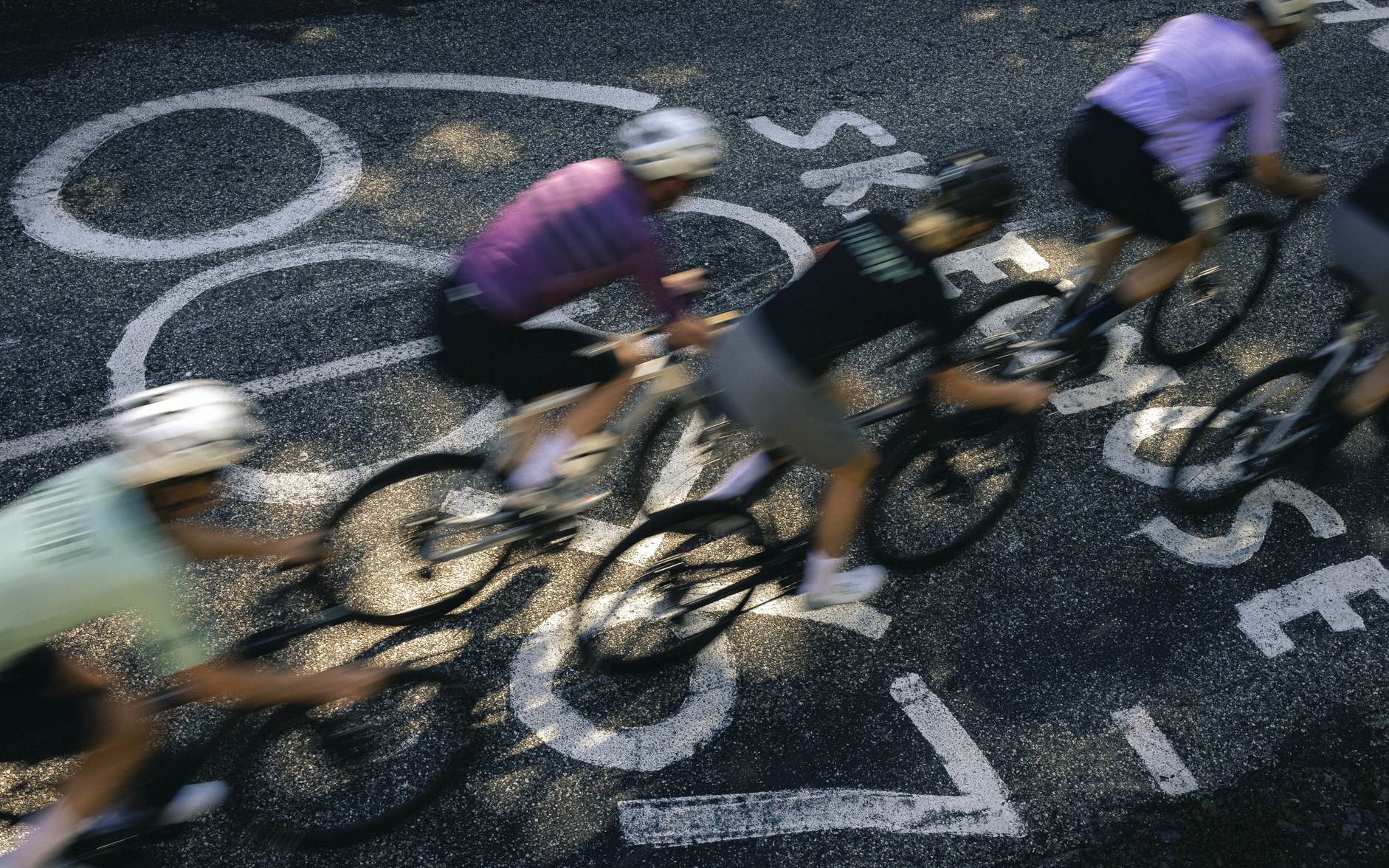 Radfahrer in Bewegung auf Straße mit Markierungen, Fokus Izalco Max, geeignet für Rennrad-Enthusiasten.
