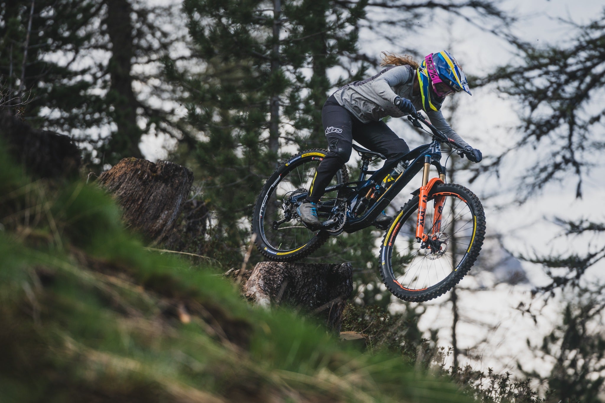 Mountainbiker*in auf GT Force Fahrrad, springt im Wald auf einem Trail, geeignet für Offroad- und Downhill-Fahrten.
