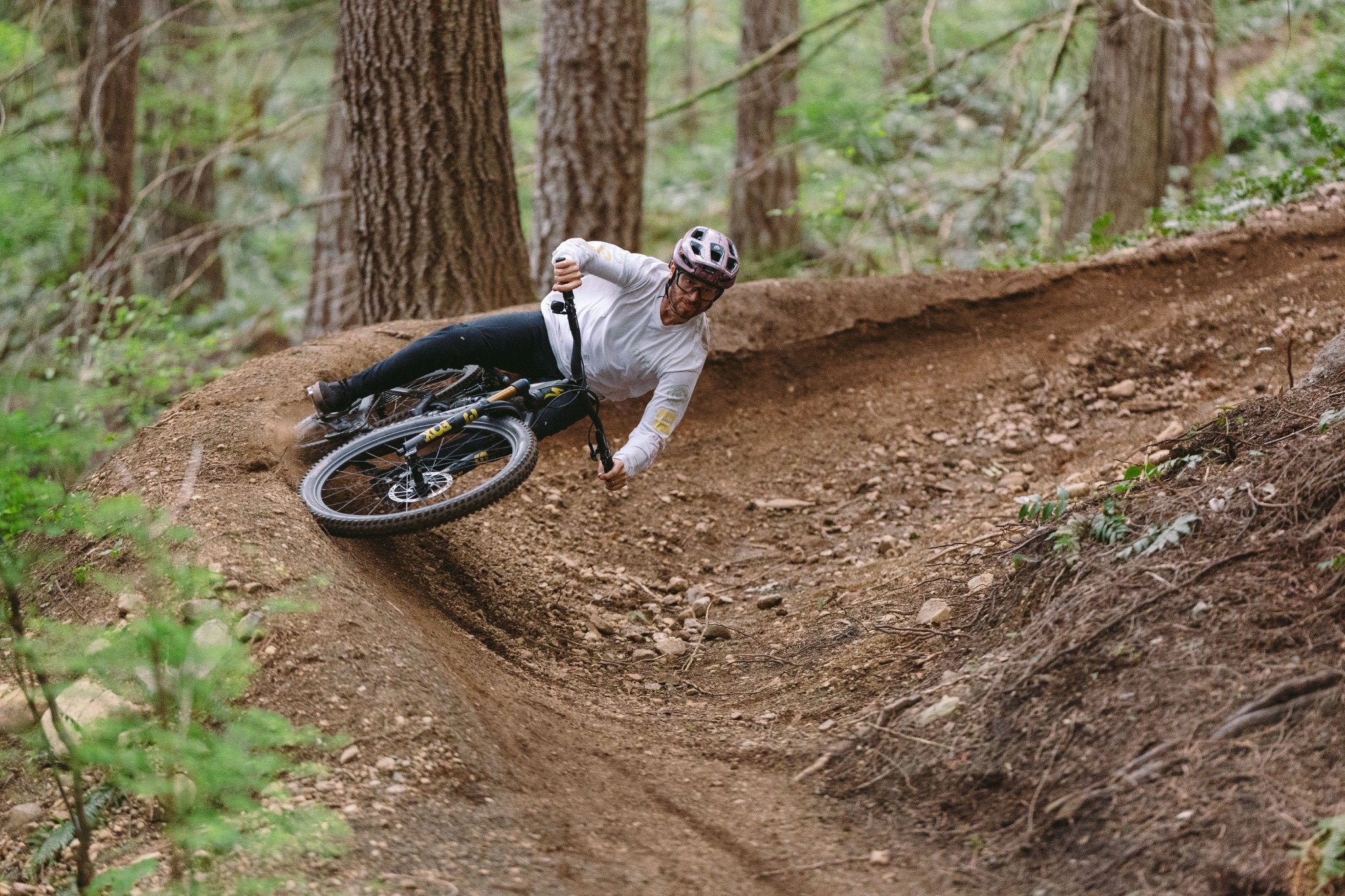 Mountainbiker auf Specialized Stumpjumper fährt dynamisch durch eine Kurve im Wald, ideal für Abenteuersportler.