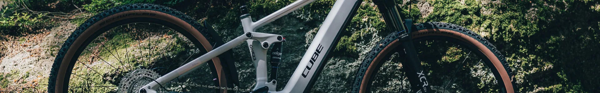 Cube Stereo Hybrid One22 mit robustem Rahmen, geeignet für Offroad-Abenteuer, seitliche Ansicht im Wald. Markennamen sichtbar.