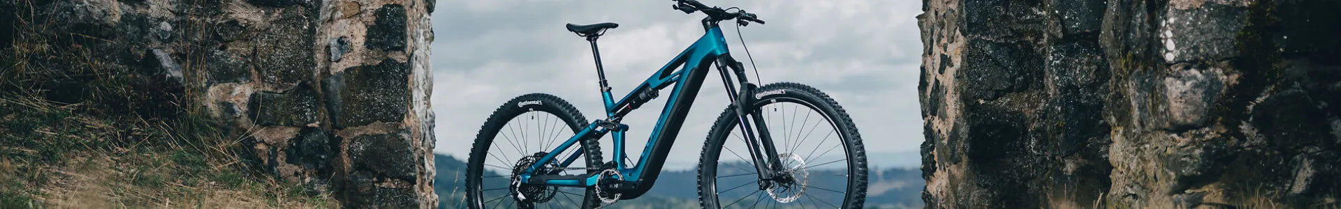 Blaues Cube Stereo Hybrid One44 steht zwischen alten Steinmauern, ideal für Offroad-Abenteuer. Reifenmarke Continental.