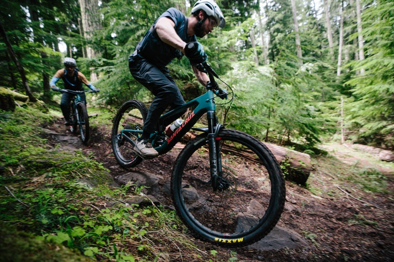 Zwei Personen fahren auf Santa Cruz Mountainbikes durch einen Waldweg, geeignet für Outdoor- und Offroad-Enthusiasten.