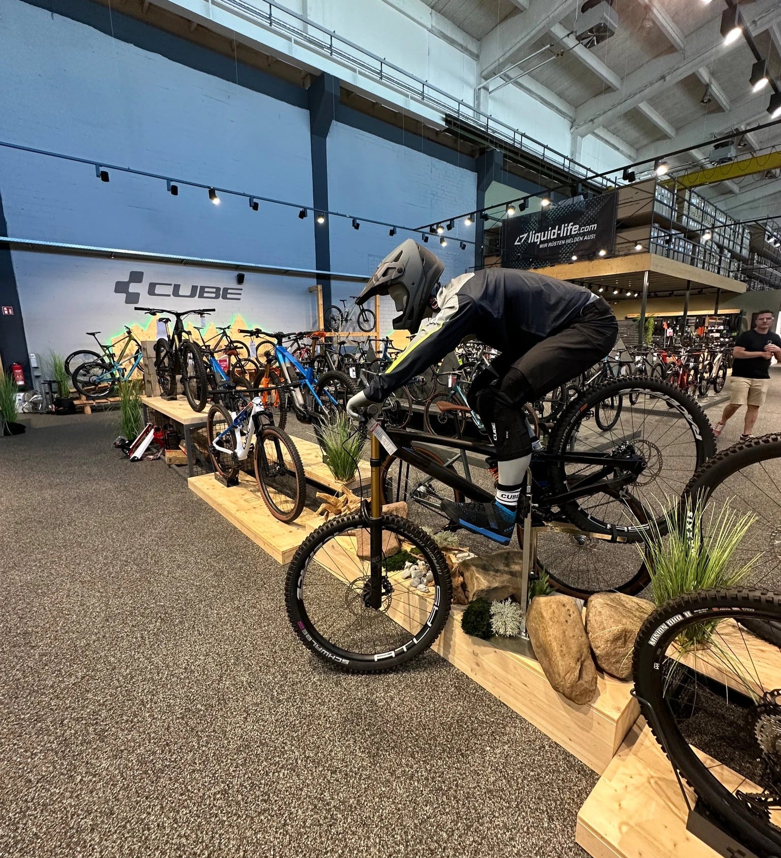 Fahrrad-Ausstellung in einem Laden, Cube-Bikes, Person posiert mit Schutzkleidung auf Mountainbike, geeignet für Outdoor-Fans.