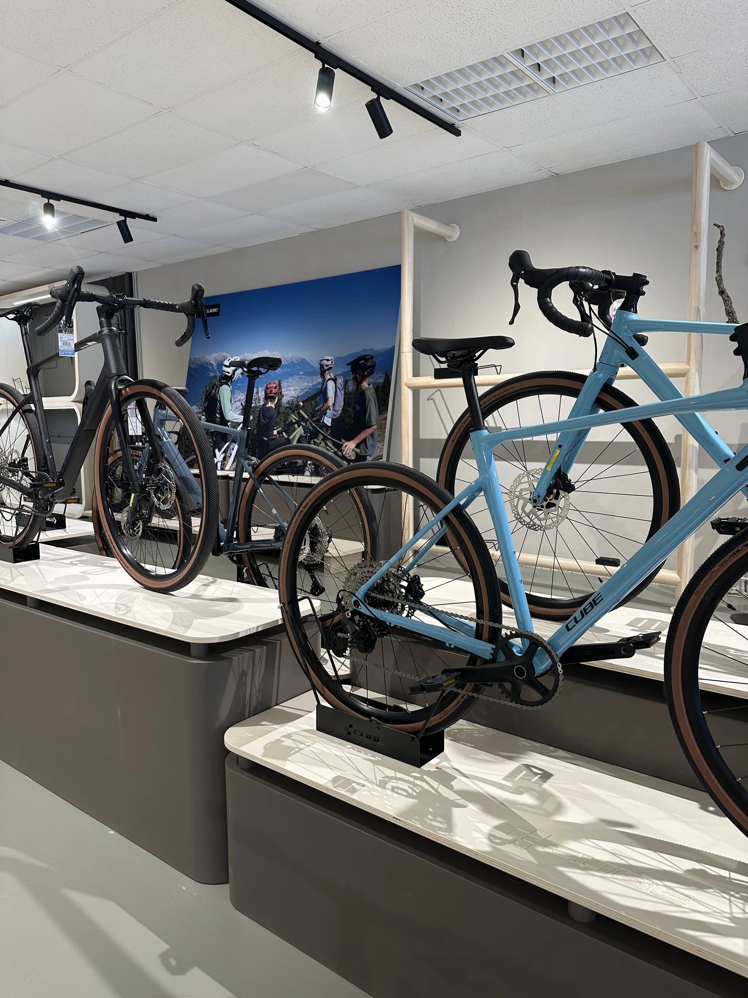 Drei Cube Fahrräder in einem Geschäft auf Podesten ausgestellt, darunter ein schwarzes und ein blaues Modell.