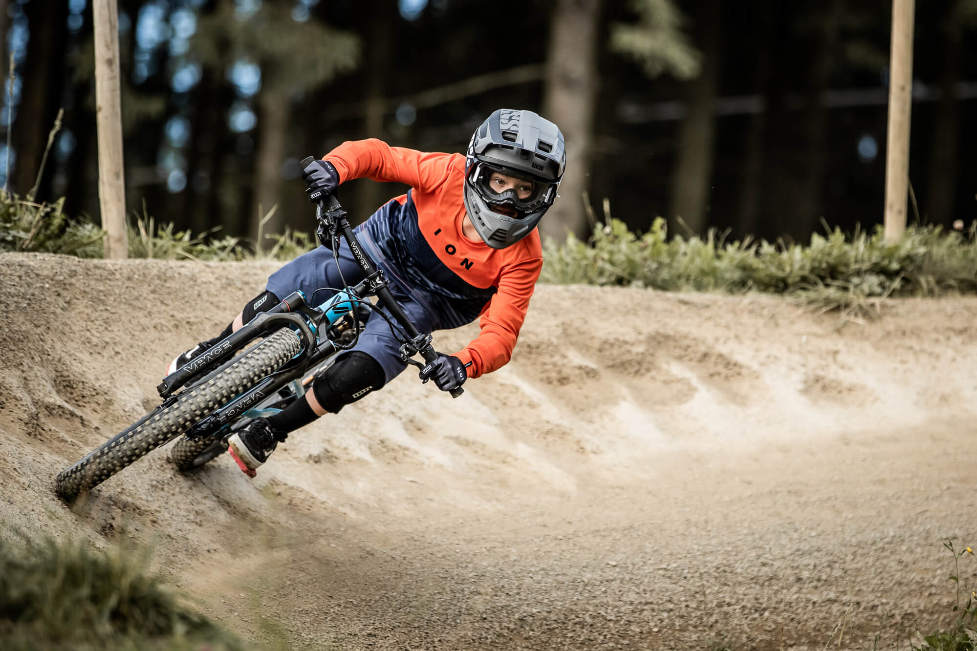 Kind mit Helm und Schutzkleidung fährt Mountainbike auf Waldstrecke. Geeignet für abenteuerlustige junge Radfahrer.