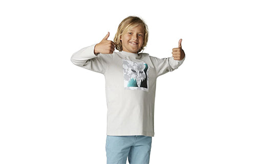 Lächelnder Junge in weißem Kindertrikot mit Bergmotiv auf der Vorderseite, Daumen hoch.