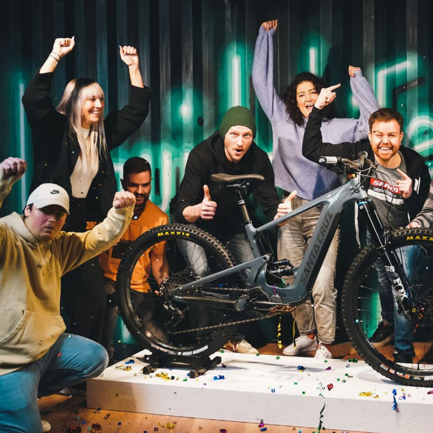 Gruppe feiert um ein Santa Cruz E-Mountainbike, geeignet für Abenteuer im Gelände und sportliche Fahrer.