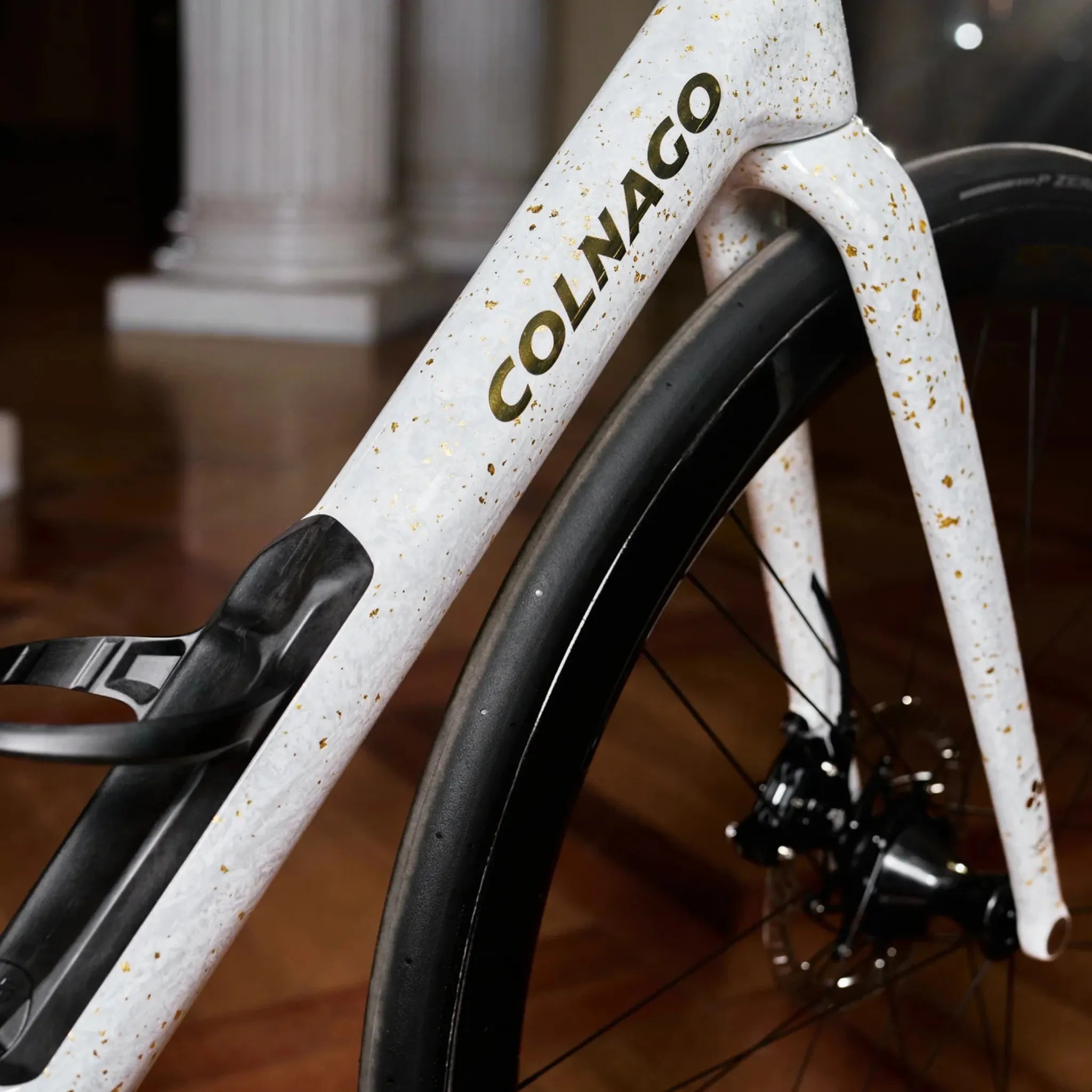 Nahaufnahme eines weißen Colnago-C72-Rennradrahmens mit goldenen Sprenkeln, geeignet für Straßenradsport.