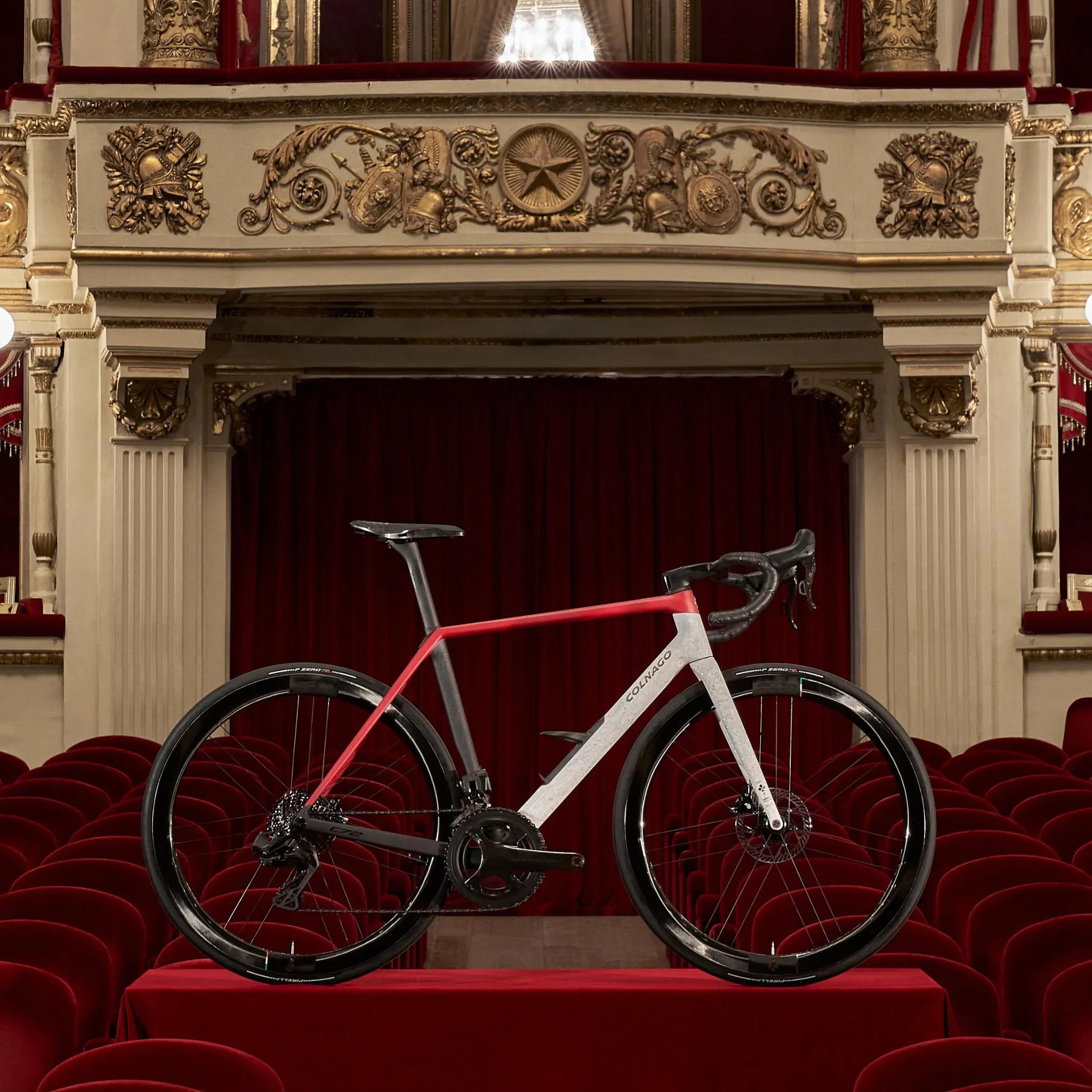 C72 Rennrad von Colnago in einem Opernsaal. Rotes und weißes Design, geeignet für Radsport-Enthusiasten.