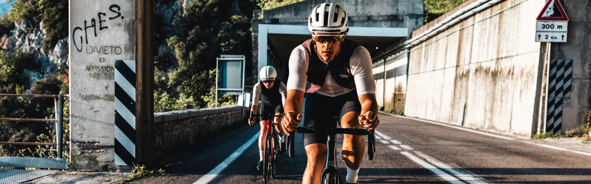 Zwei Superior Radfahrer in Sportkleidung fahren durch einen Tunnel auf einer Landstraße. Sie tragen Helme und Sonnenbrillen.