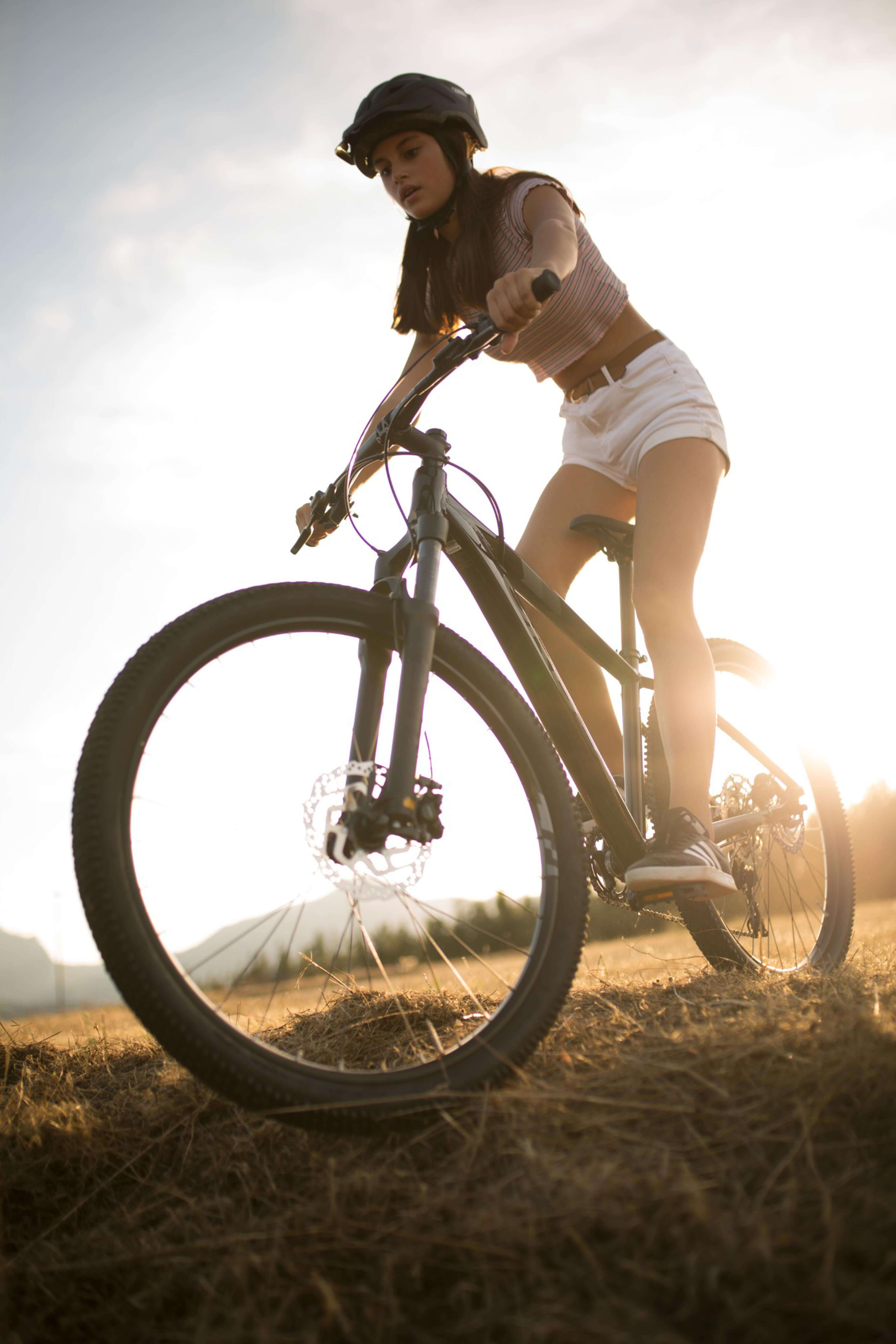 Mädchen auf einem Mountainbike im Freien bei Sonnenuntergang, trägt Helm. Modell: Orbea MX Junior.