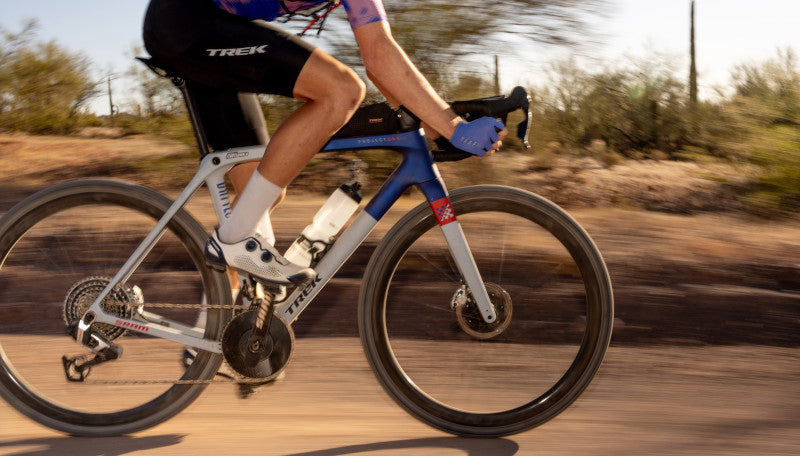 Radfahrer auf Trek Checkmate Fahrrad in Bewegung auf einer staubigen Straße, geeignet für sportliche Outdoor-Aktivitäten.