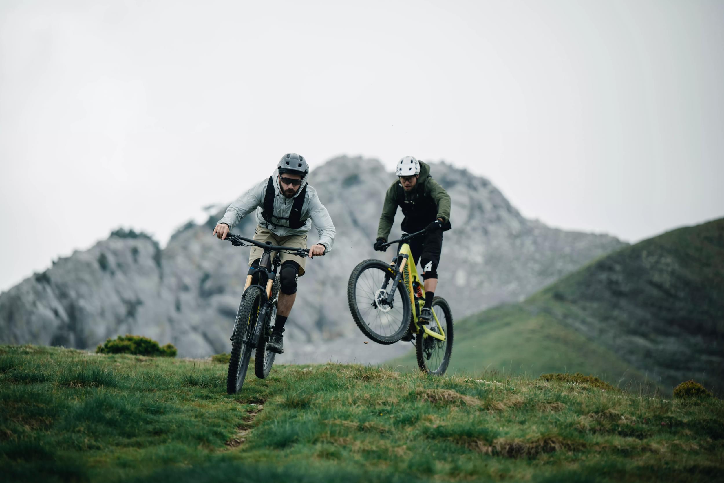 Zwei Mountainbiker fahren mit Orbea Occam Rädern im Gelände vor einer Bergkulisse.