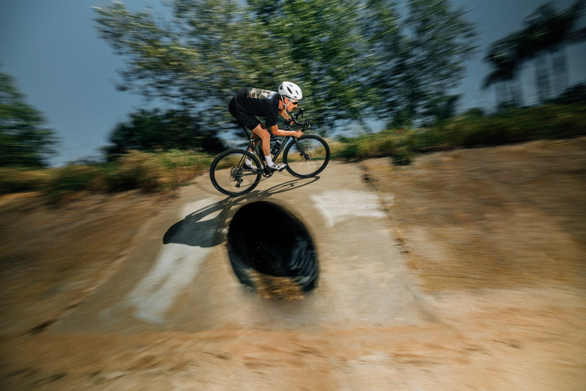 Radfahrer mit Specialized Crux Fahrrad fährt über eine Betonrampe in einem Outdoor-Gelände.