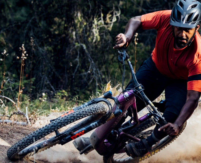 Mann mit Helm fährt in Kurve auf Trailbike im Wald.