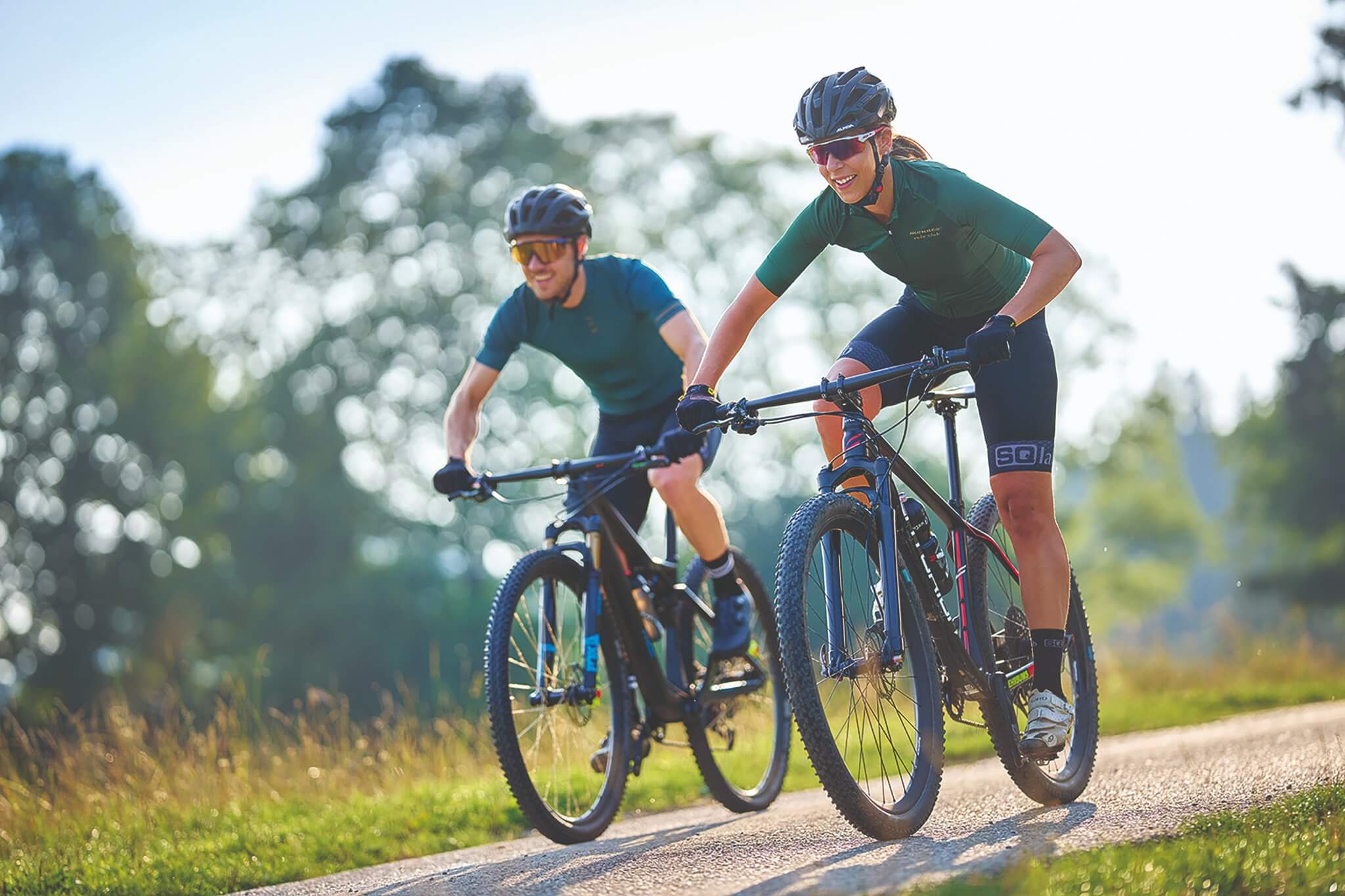 Zwei Radfahrer auf Mountainbikes im Freien, tragen Fahrradhelme und Sportbekleidung von SQlab.