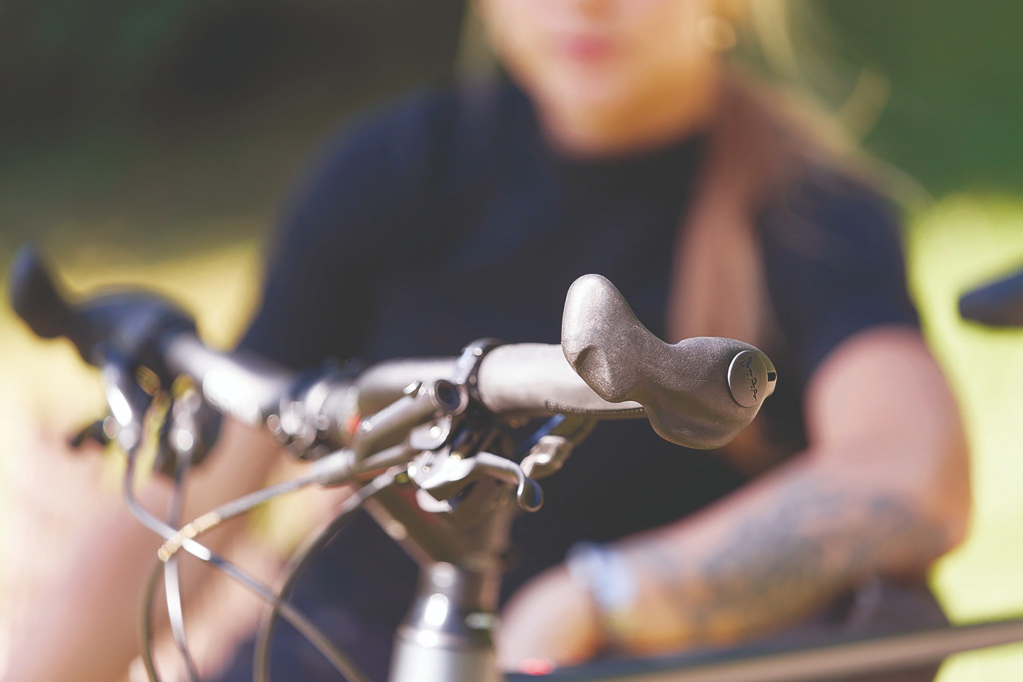 Fahrradlenker mit ergonomischem SQlab-Griff, im Vordergrund, unscharfe Person im Hintergrund.