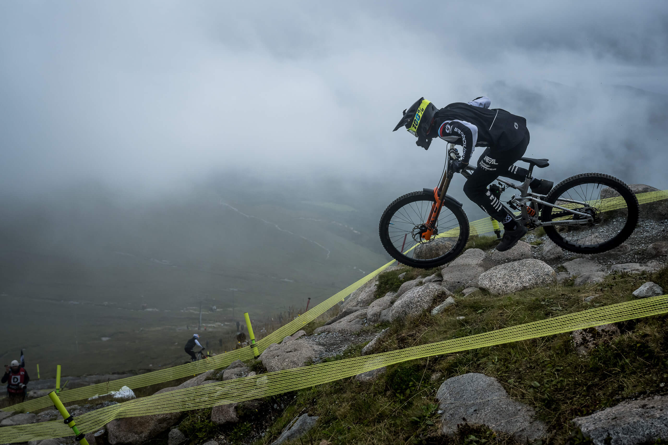 Mountainbiker fährt bei Nebel einen steinigen Hang hinunter, Mondraker Bike für Downhill-Abenteuer.