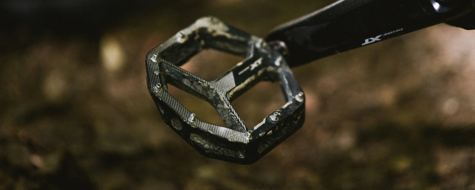 Shimano MTB-Pedal DEORE XT PD-M8040 auf Waldboden, robustes Design für Mountainbiking.