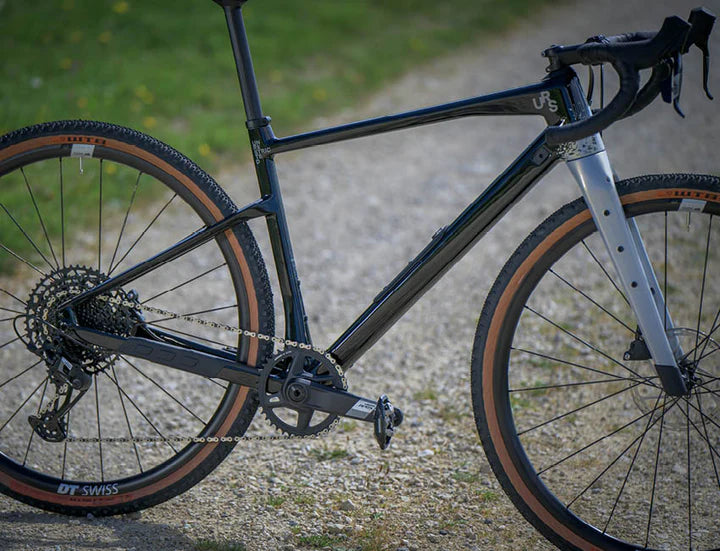 Schwarzes BMC URS Gravelbike auf Schotterweg mit DT Swiss Rädern, ideal für Offroad-Fahrer.