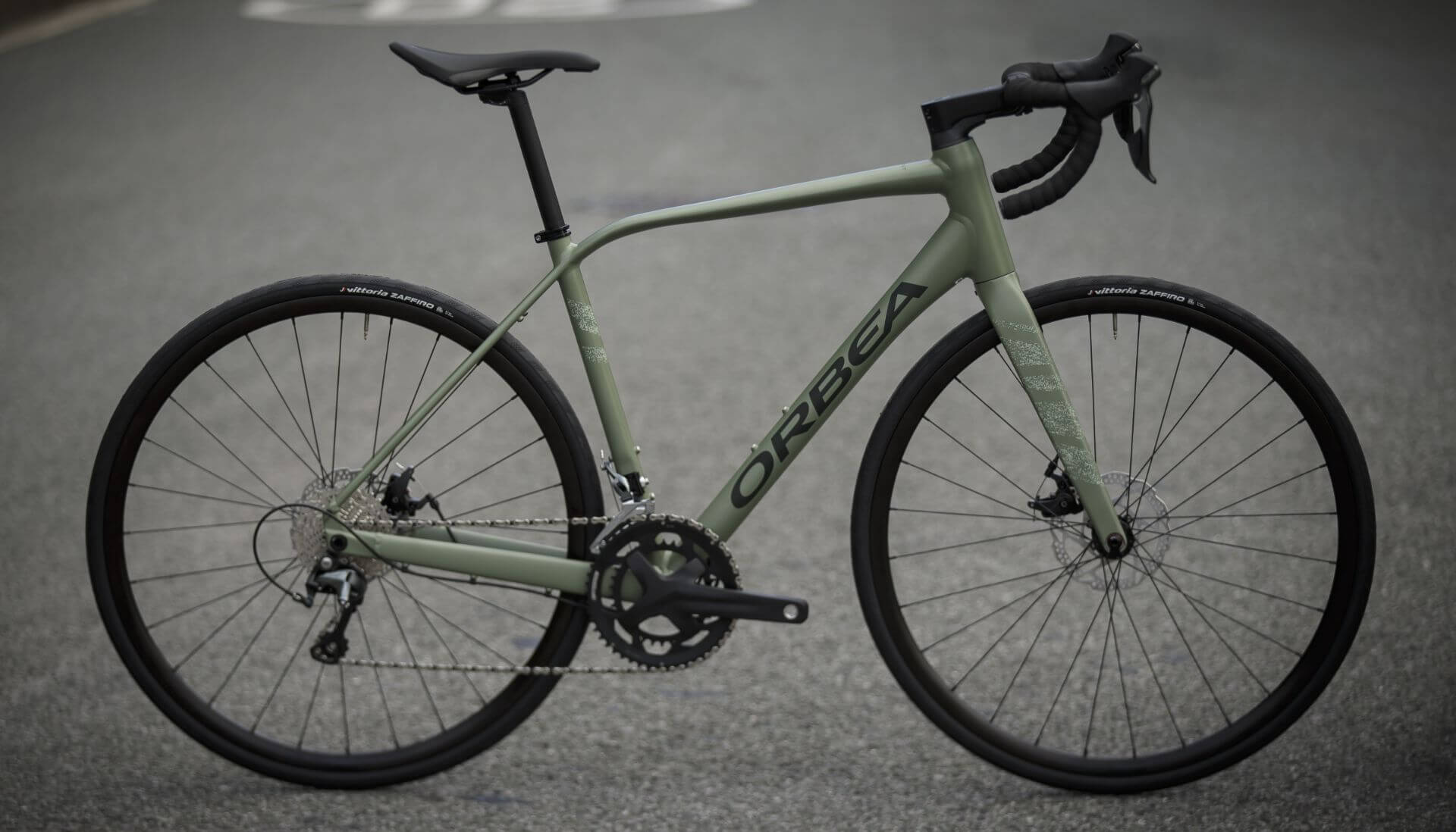 Orbea Avant Rennrad in Grün auf Straße, aerodynamisches Design, ideal für Sportler und Radfahrbegeisterte.