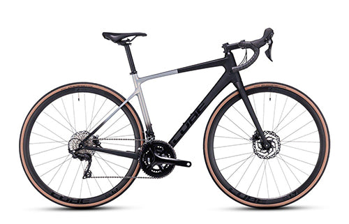 Rennrad Cube Axial mit schwarzem und grauem Rahmen, Scheibenbremsen und braun-schwarzen Reifen, ideal für Radsportler.