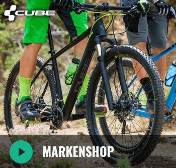 Zwei Personen fahren Cube Hardtail-Mountainbikes mit Straßenausstattung auf einem unbefestigten Weg.