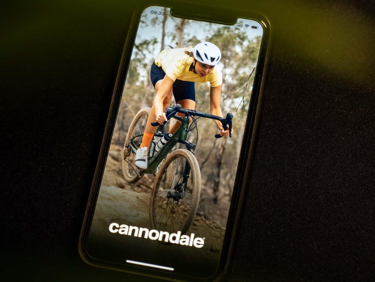 Smartphone zeigt ein Bild eines Radfahrers auf einem Cannondale Synapse Gravel-Bike im Wald.