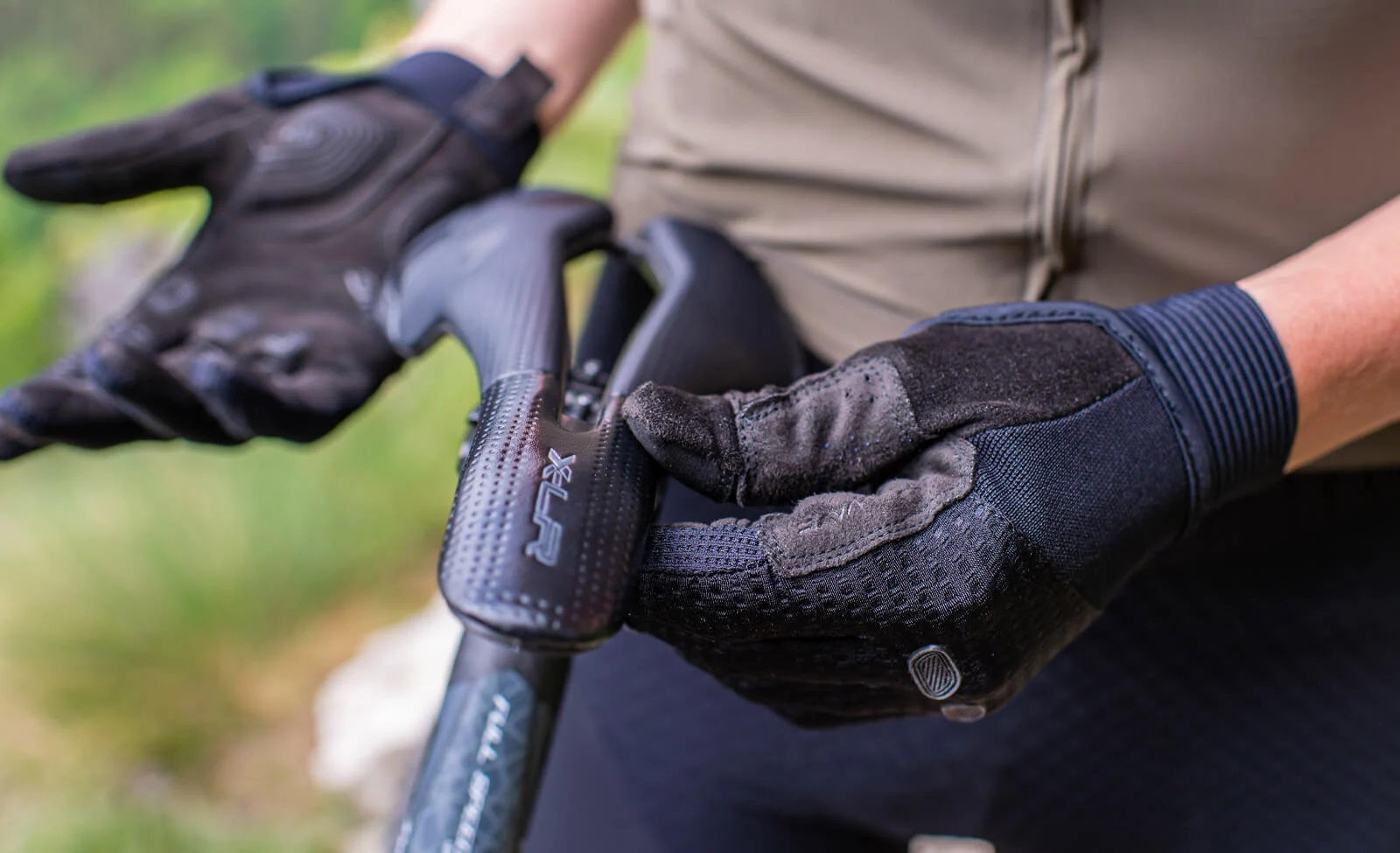 Person mit gepolsterten Fahrradhandschuhen hält einen Fahrradsattel; Label „XLR“ sichtbar. Ideal für Radfahrer.