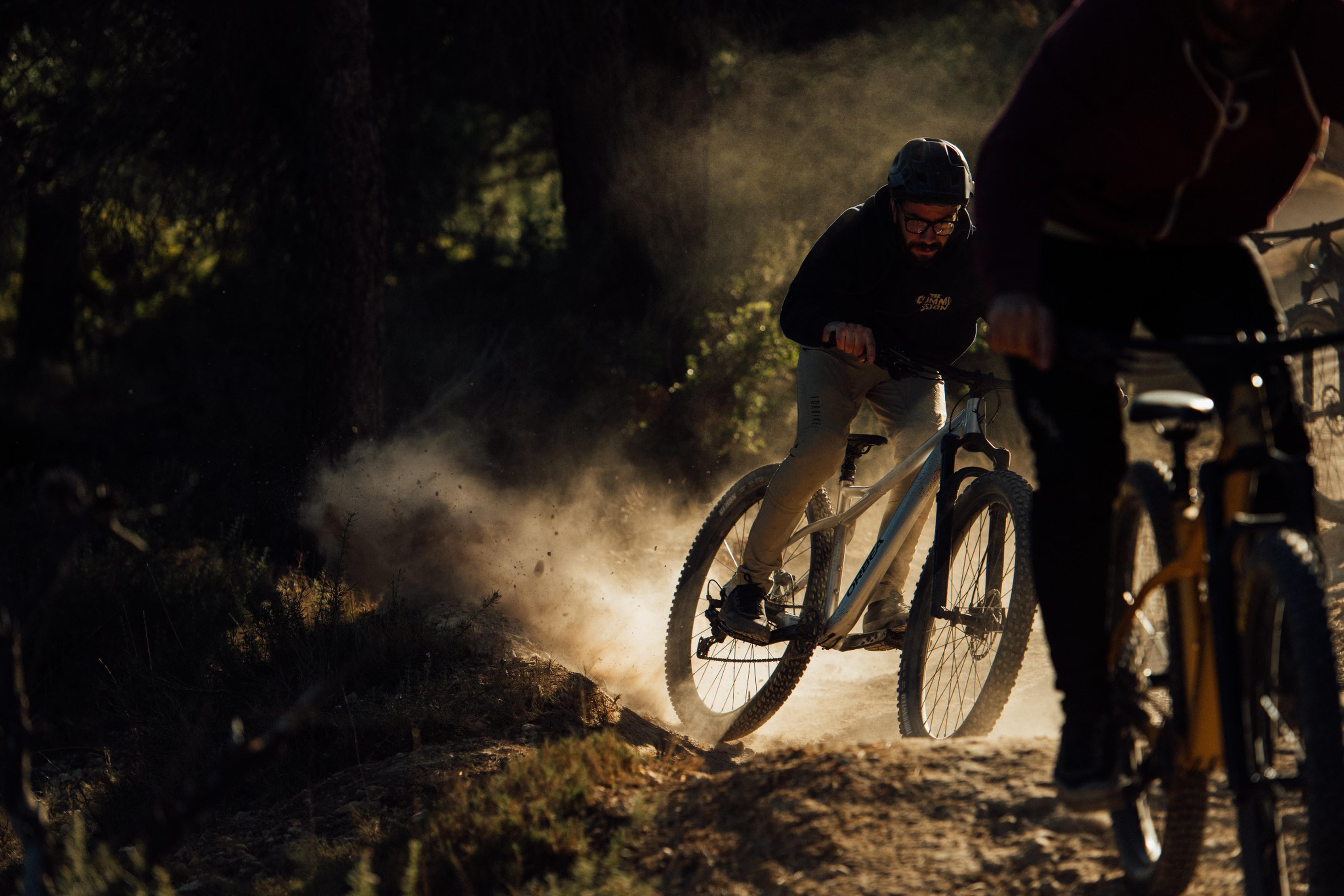 Zwei Mountainbiker fahren im Wald auf staubigen Wegen. Fokus auf das Orbea Laufey Mountainbike.