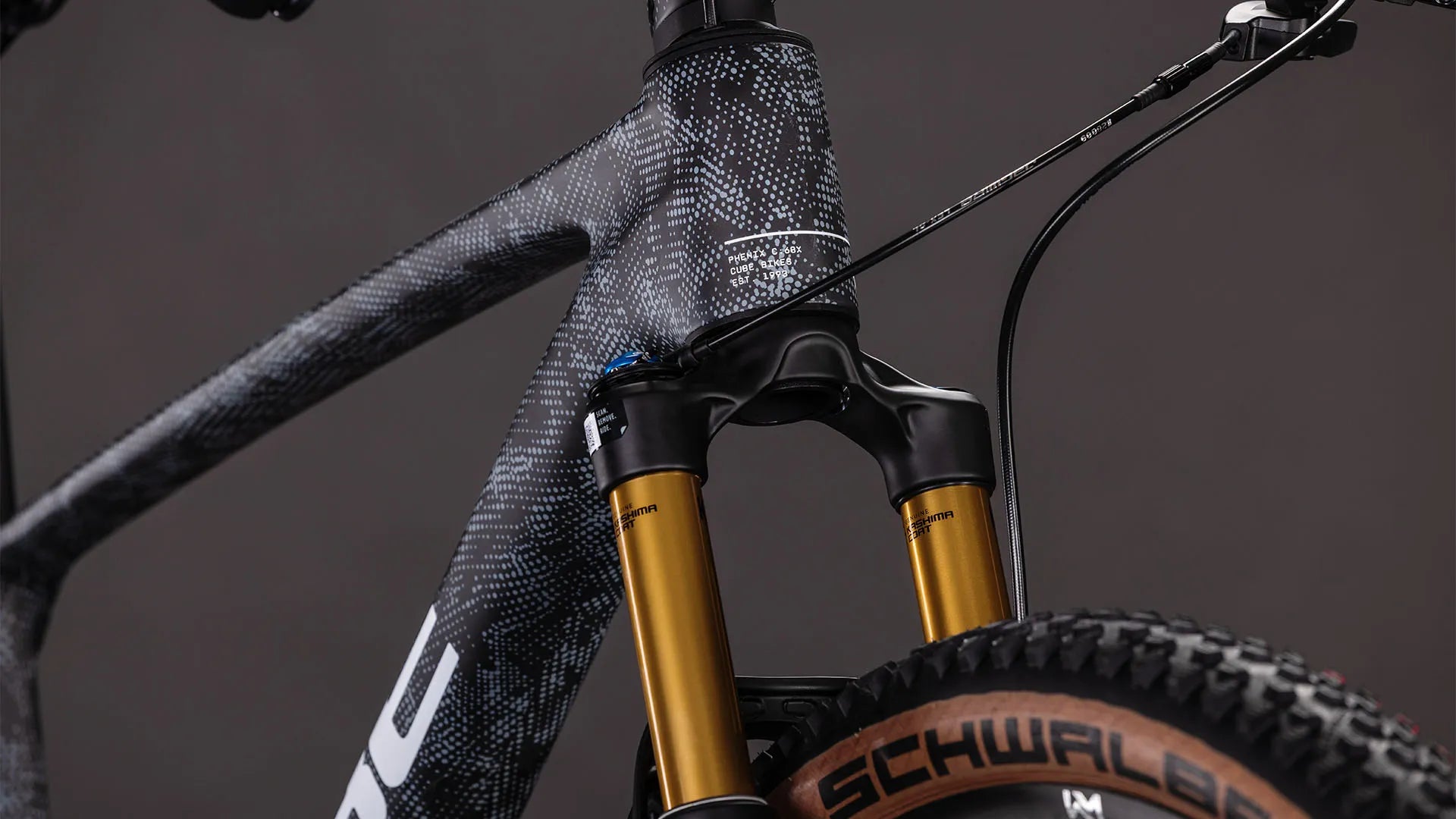 Nahaufnahme eines CUBE PHENIX C:68X SLX-Rahmens in Grau mit Federgabel und Schwalbe-Reifen, geeignet für Offroad-Abenteuer.