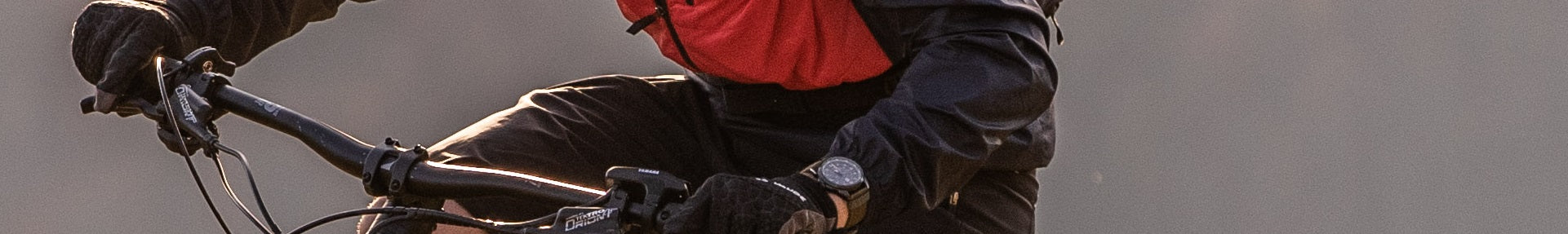Person auf Fahrrad in Sportkleidung mit rotem Rucksack, fährt sportlich im Freien. Haibike-Alltrack Lenker erkennbar.