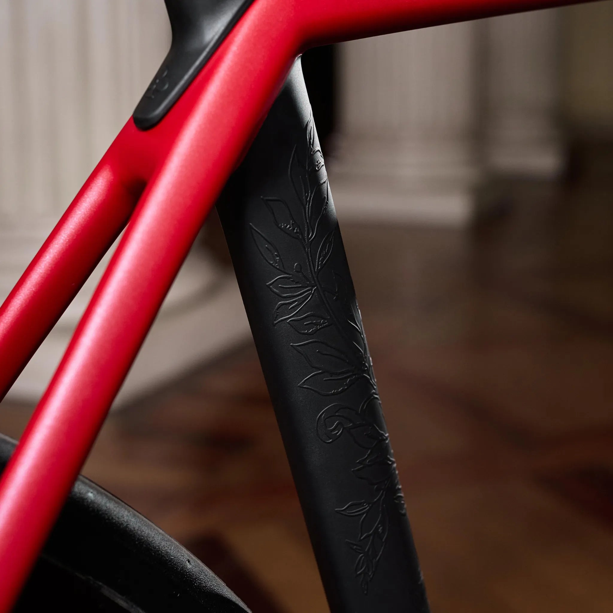 Nahaufnahme des rot-schwarzen Colnago C72 Fahrradrahmens mit floralem Muster auf der Sattelstütze. Ideal für stilbewusste Radfahrer.