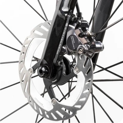 Nahaufnahme einer Fahrrad-Scheibenbremse an einem schwarzen Rahmen. Markenname oder Modell nicht erkennbar.