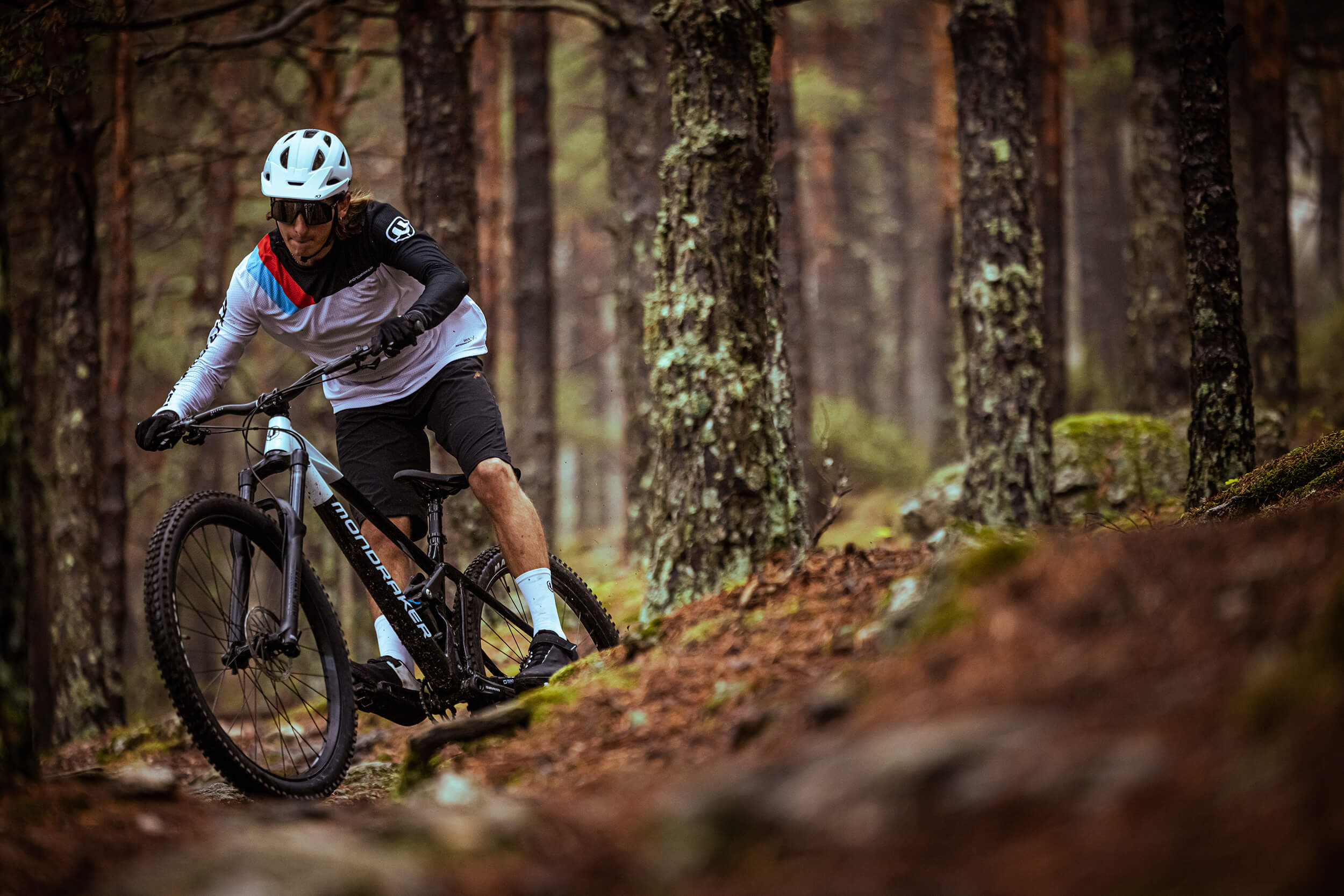 Mountainbike-Fahrer im Wald mit Mondraker Raze, ideal für anspruchsvolle Trails. Geeignet für Abenteuer-Enthusiasten.